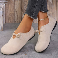 Beige loafers with rope details worn by a person on a stone floor.