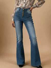 Flared blue jeans with button details worn by a person on a beige background