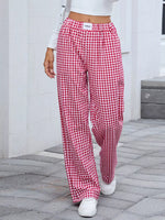 Person wearing red and white checkered pants on a stone pavement.