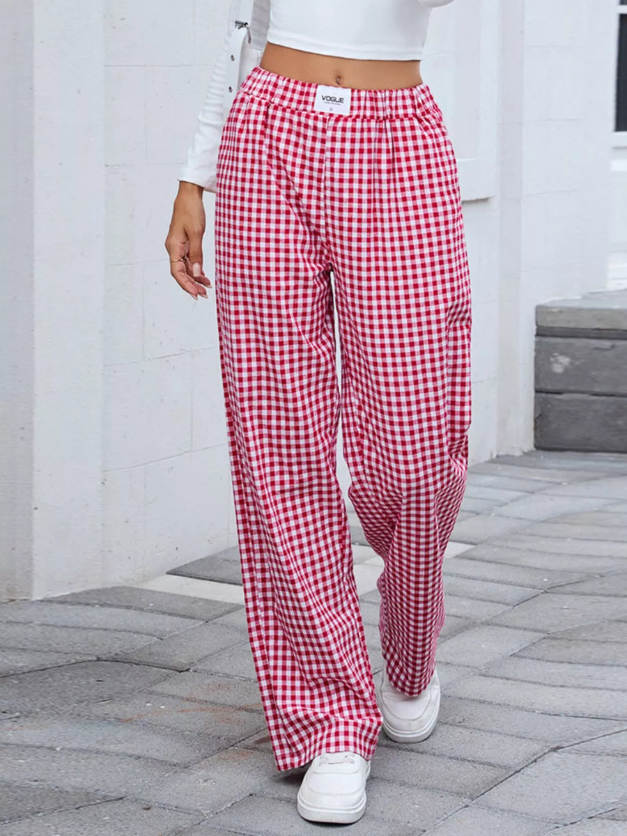 Person wearing red and white checkered pants on a stone pavement.