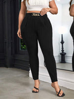 Person wearing black pants with a gold chain belt in an indoor setting
