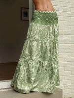 Green patterned skirt worn by a person against a light brick wall.