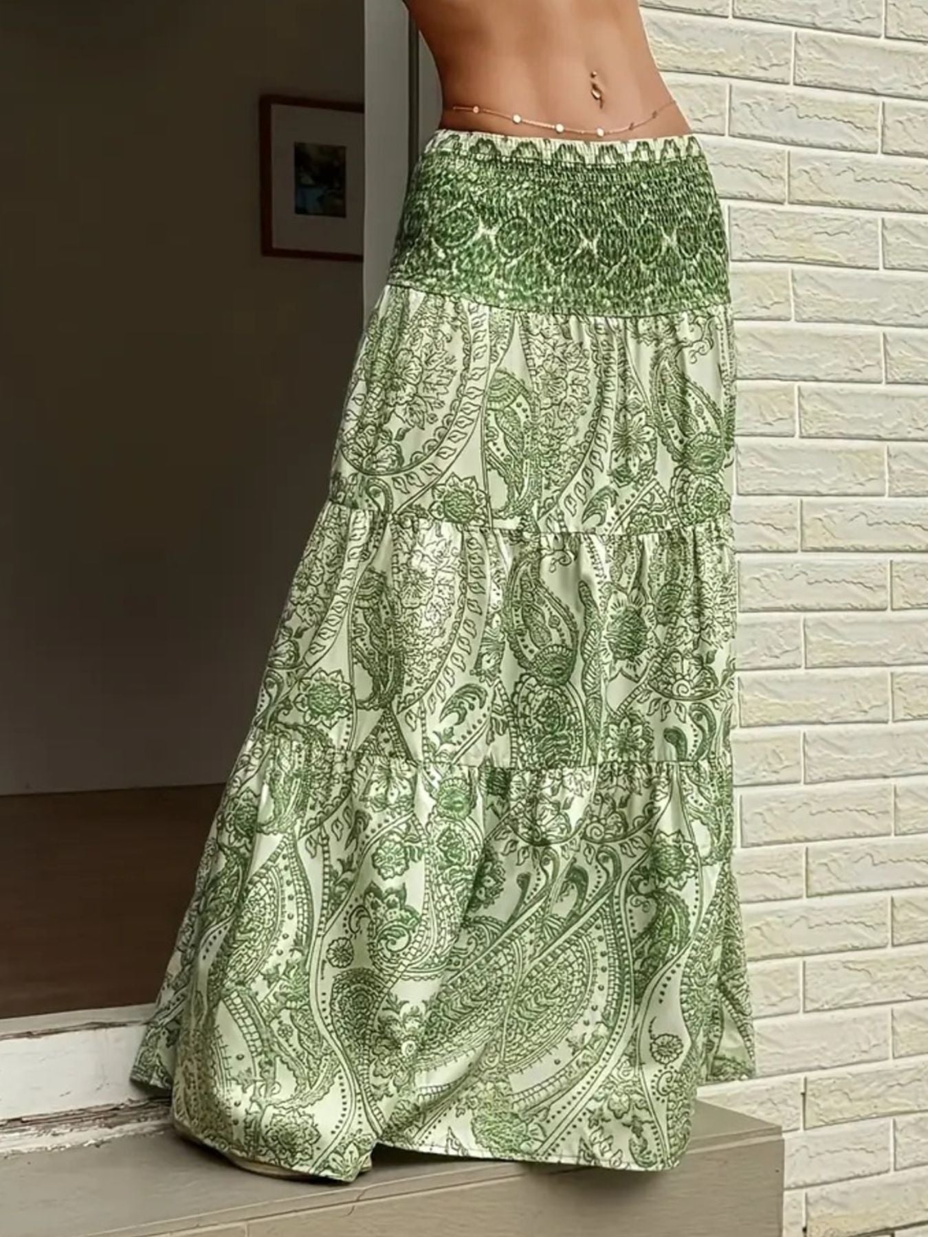 Green patterned skirt worn by a person against a light brick wall.