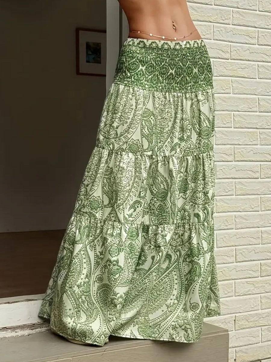 Green patterned skirt worn by a person against a light brick wall.