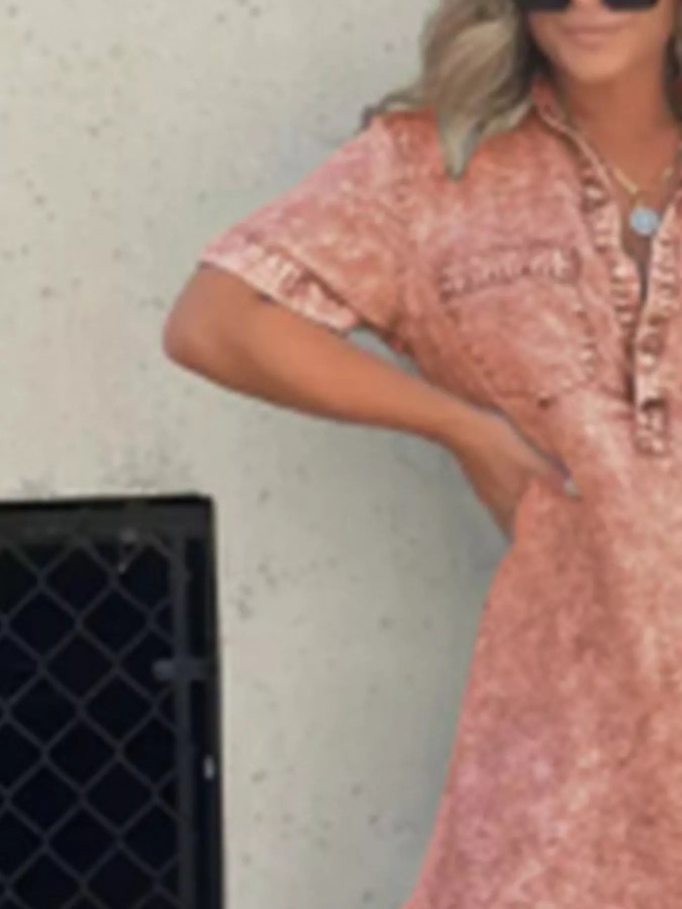 Person wearing a pink patterned dress standing against a light-colored wall.