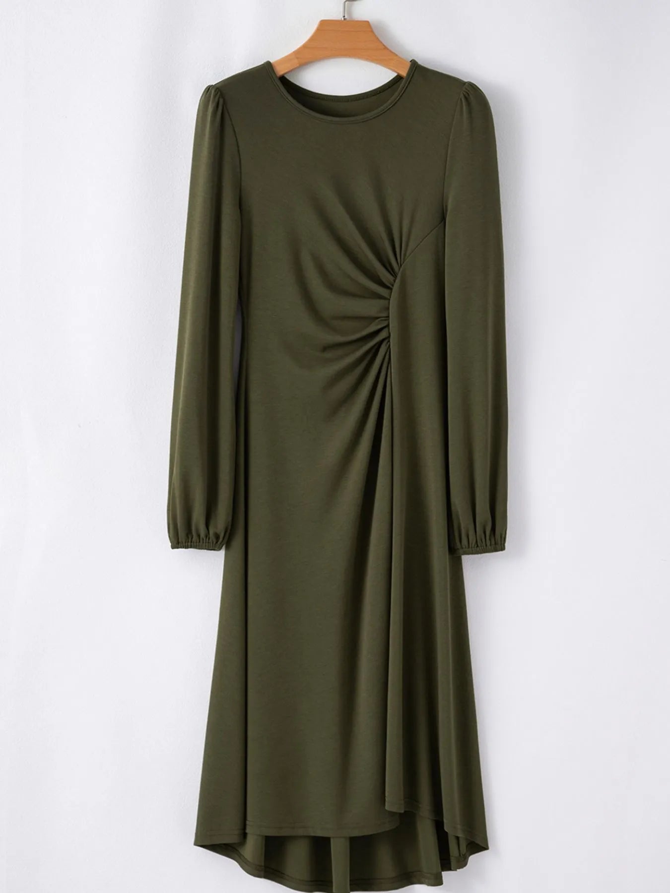Green dress with long sleeves on a hanger against a white background