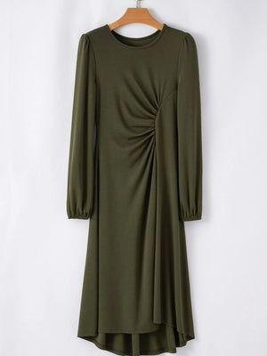 Green dress with long sleeves on a hanger against a white background