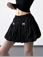 Black skirt with white bows worn by a person on a plain background