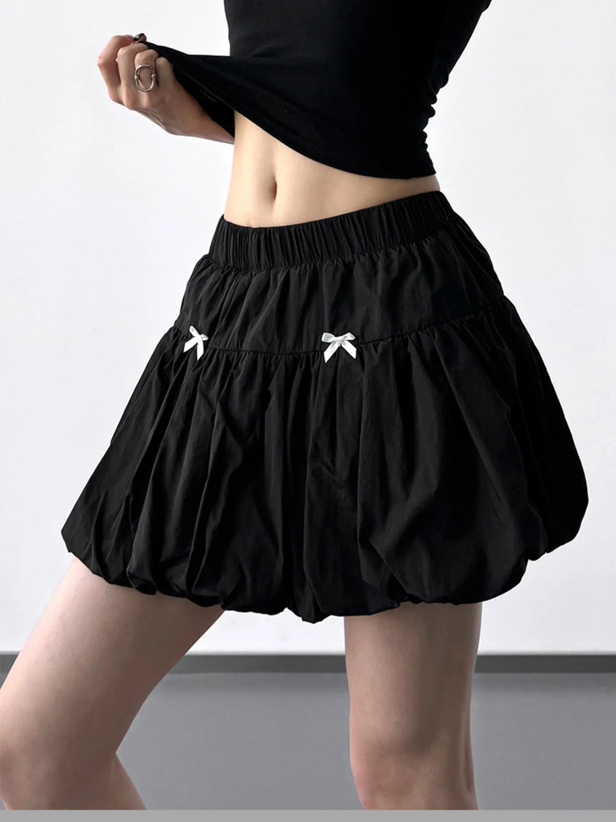 Black skirt with white bows worn by a person on a plain background