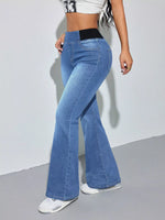 Person wearing blue flared jeans on a plain background