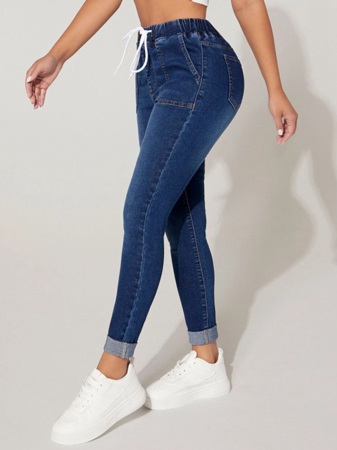 Blue jeans worn by a person on a plain background
