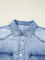 Close-up of a light blue denim shirt with collar and buttons on a beige background