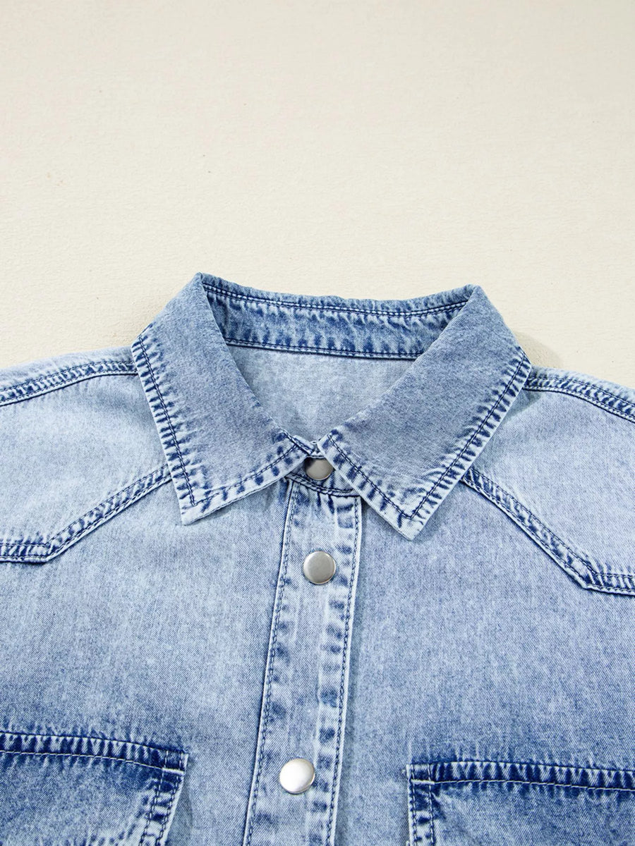 Close-up of a light blue denim shirt with collar and buttons on a beige background