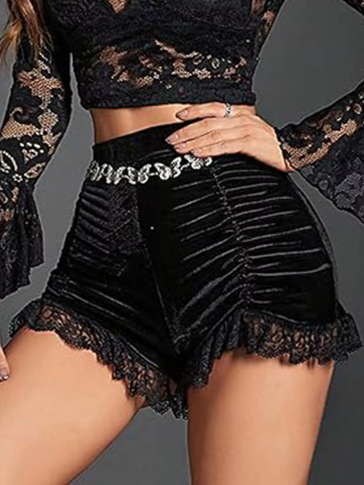 Person wearing black lace top and shorts on a gray background