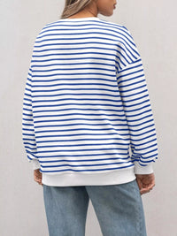 Person wearing a blue and white striped sweater with a plain background