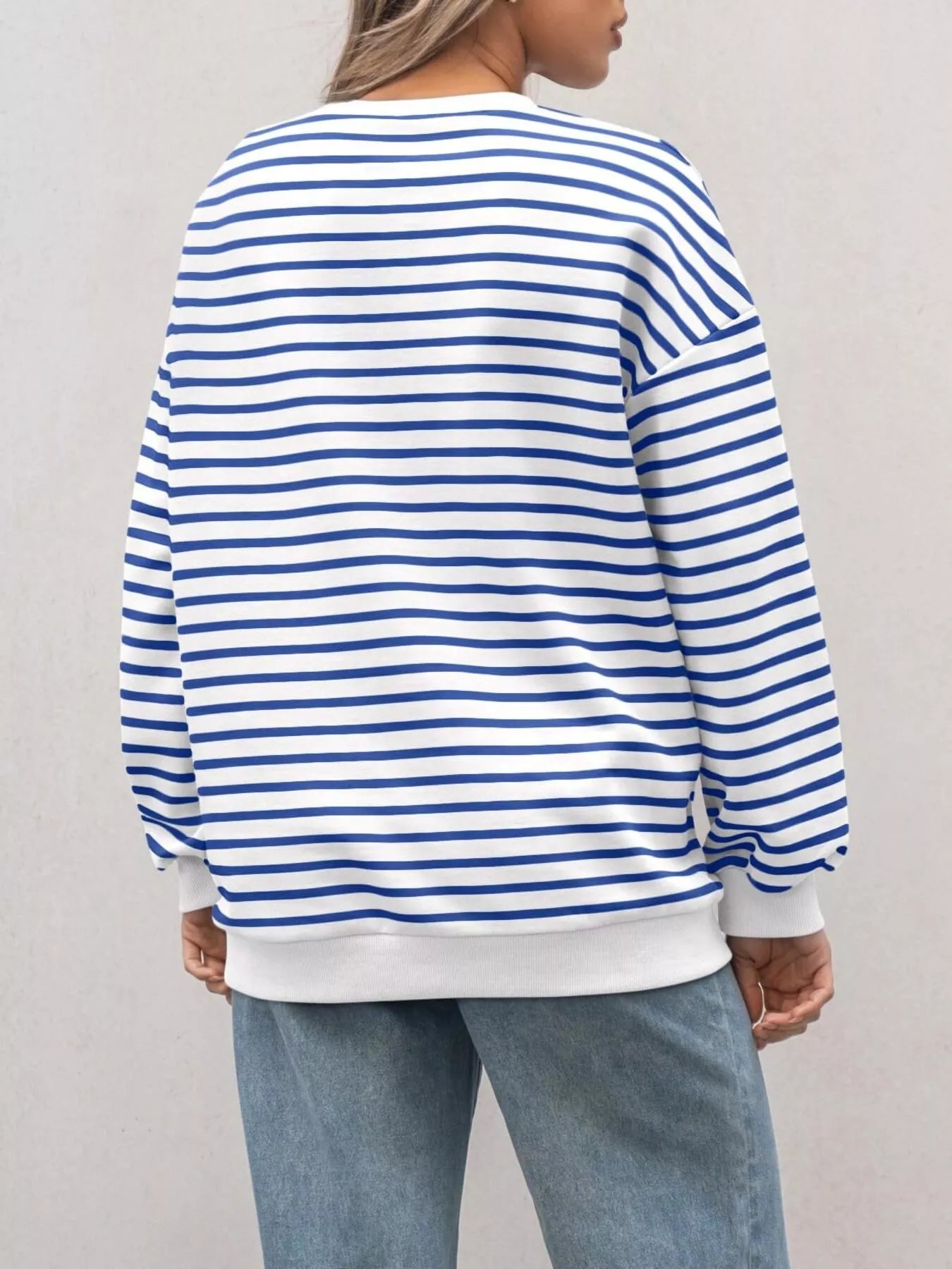 Person wearing a blue and white striped sweater with a plain background