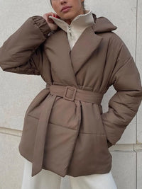 Brown puffer coat worn by a person against a light-colored wall.