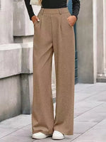 Person wearing beige wide-leg pants standing against a stone wall.