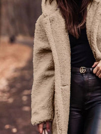 Person wearing a beige coat with a blurred natural background