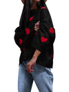 Black top with red heart patterns worn by a person on a white background