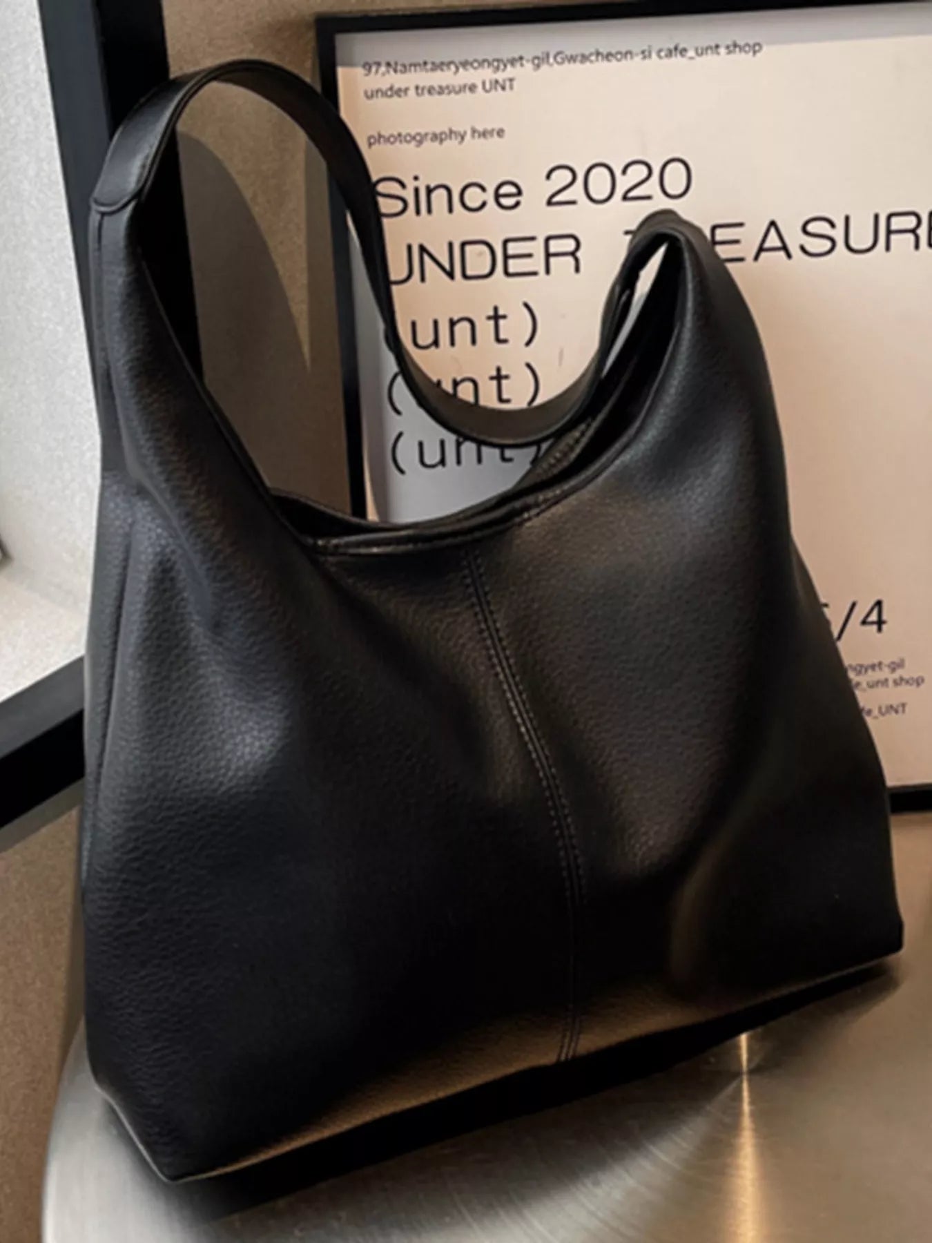 Black handbag on a reflective surface with a blurred background
