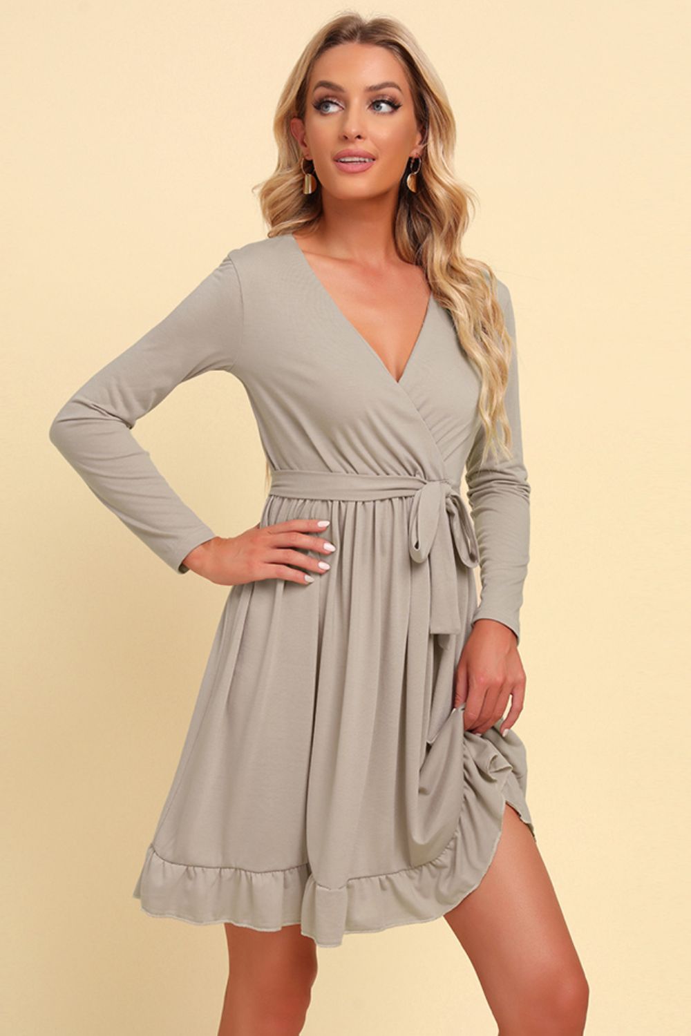 Woman wearing a gray wrap dress on a beige background
