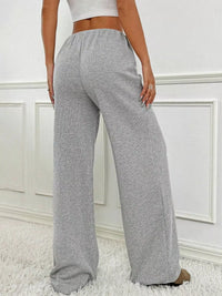 Gray sweatpants worn by a person on a white background