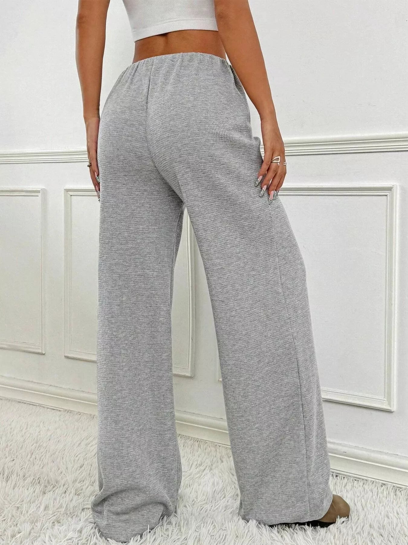 Gray sweatpants worn by a person on a white background
