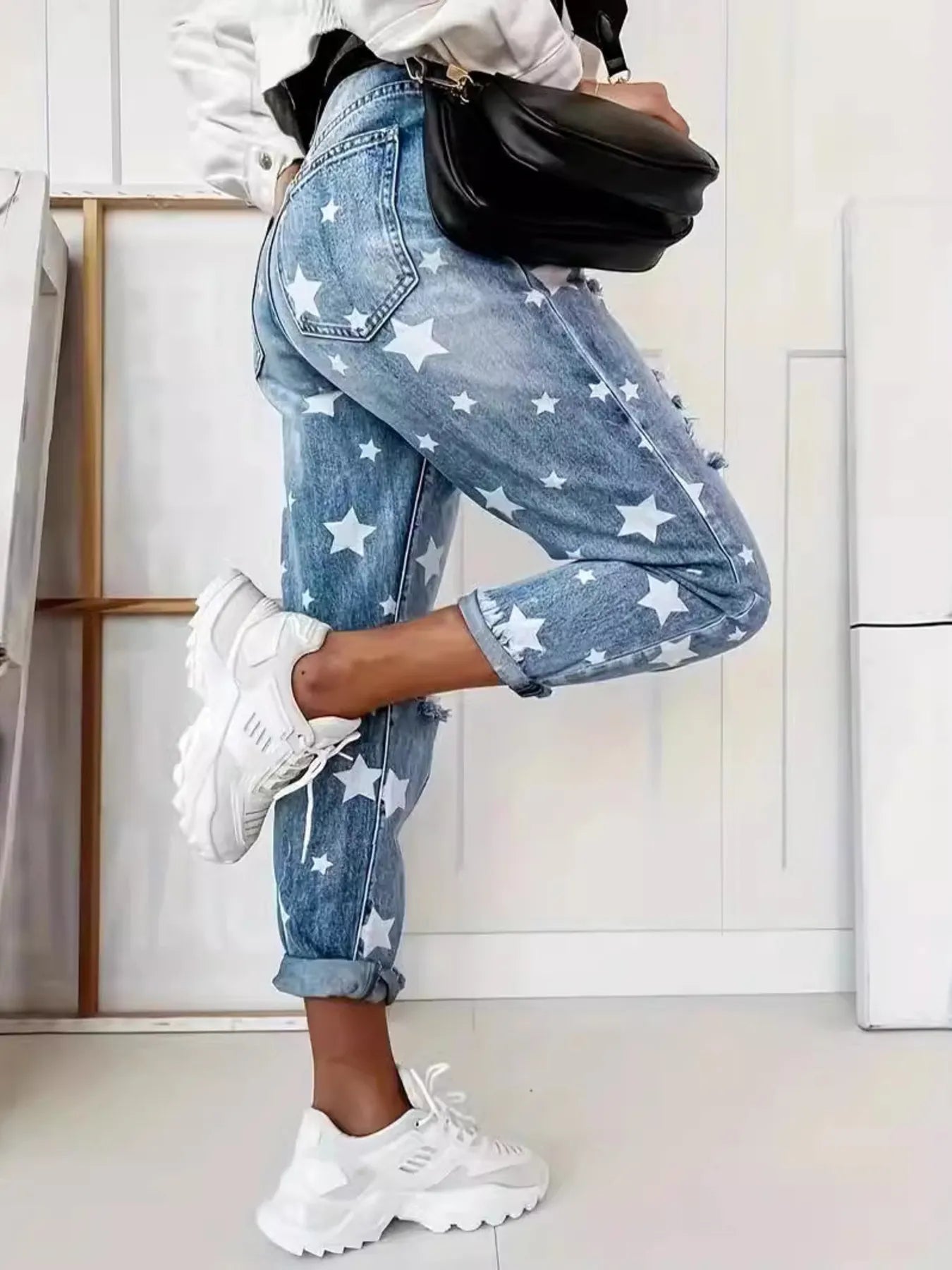 Person wearing star-patterned jeans and white sneakers in a minimal indoor setting