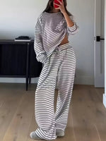 Person wearing a gray and white striped outfit in a room with a desk and door.