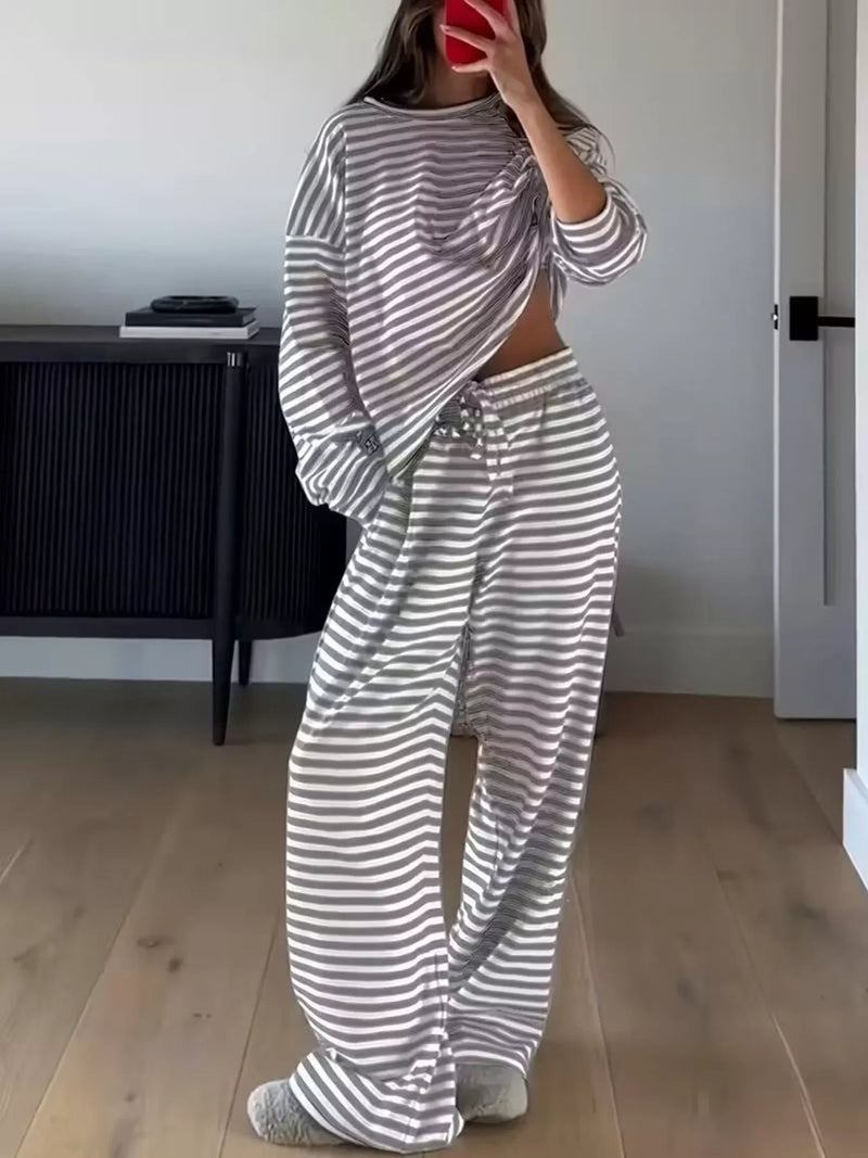 Person wearing a gray and white striped outfit in a room with a desk and door.
