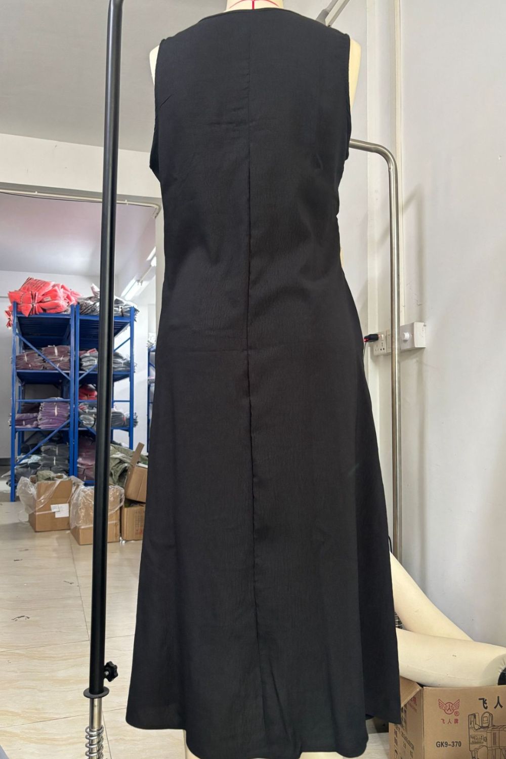 Black sleeveless dress on a mannequin in a warehouse setting