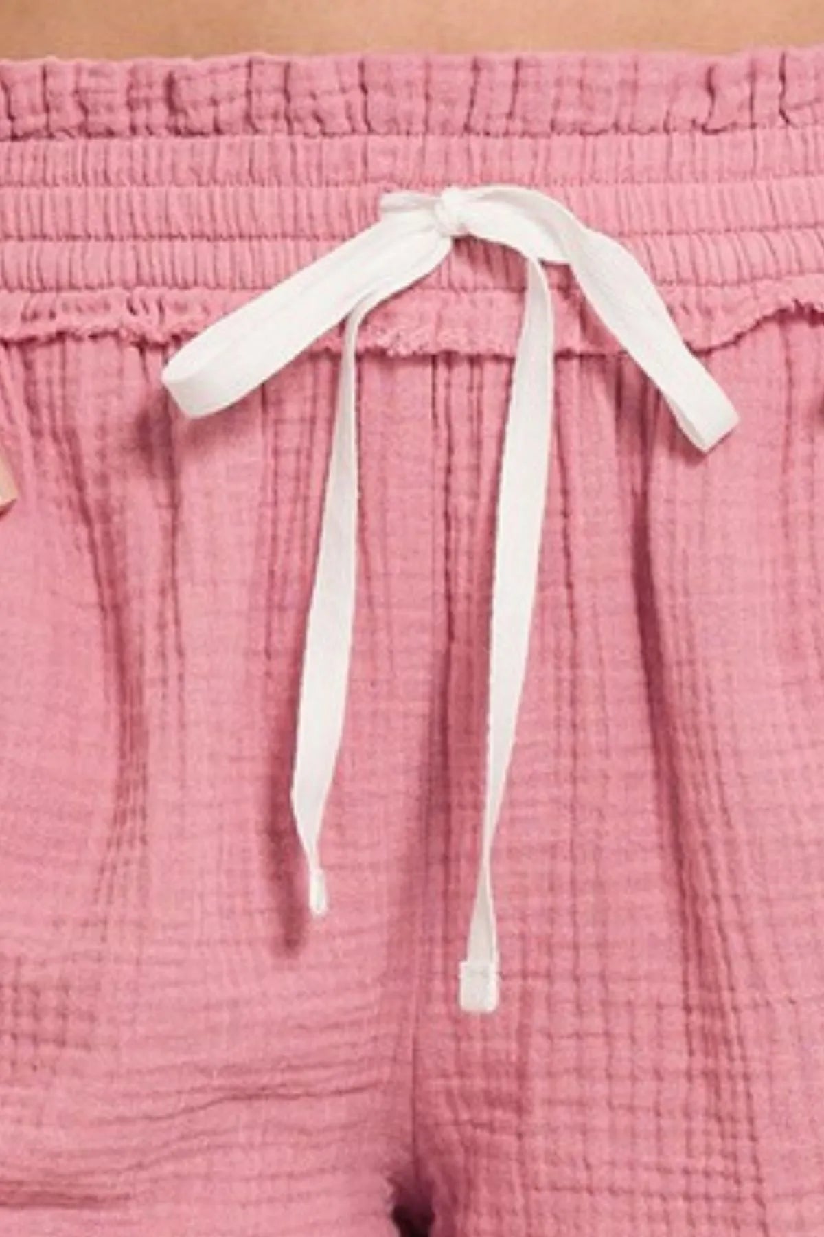 Close-up of pink pants with a white drawstring on a matching pink background