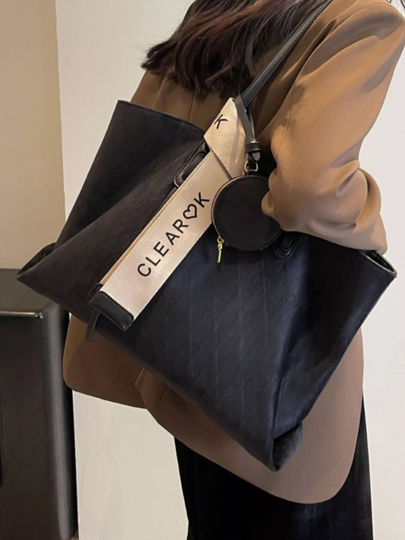 Person holding a black bag with 'CLEARQX' branding against a neutral background