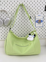 Light green handbag with a plush toy attached, on a white surface with a white pegboard background.