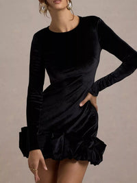 Black long-sleeve dress with ruffled hem on a neutral background