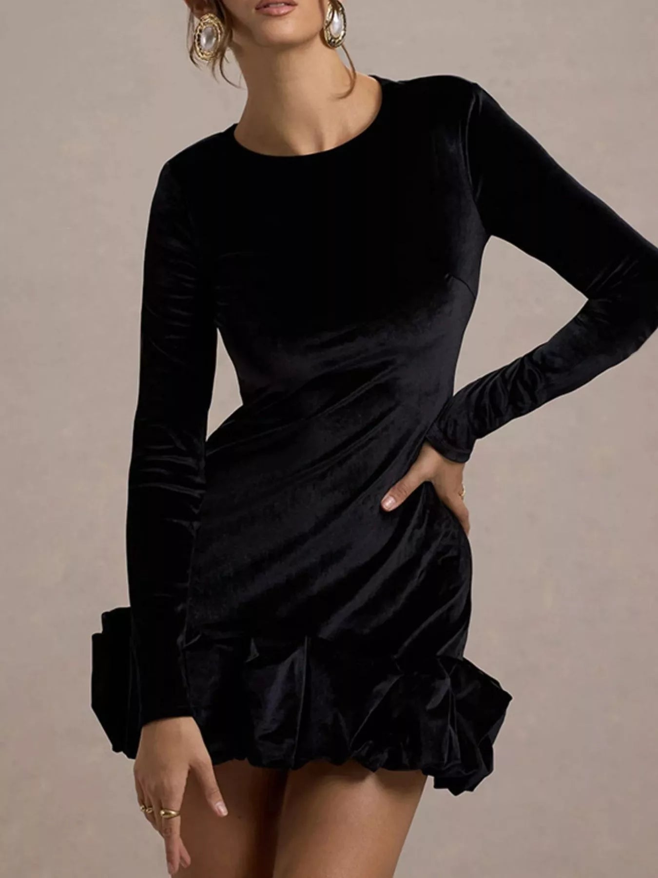Black long-sleeve dress with ruffled hem on a neutral background
