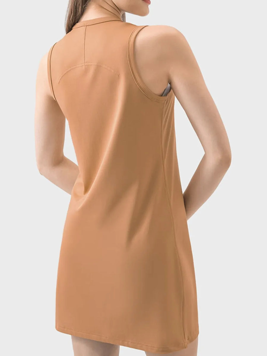 Woman wearing a mustard yellow sleeveless dress against a light gray background