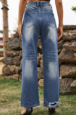 Person wearing blue jeans standing in front of a stone wall.