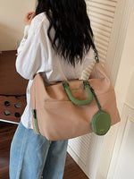 Person holding a beige handbag with green accents indoors