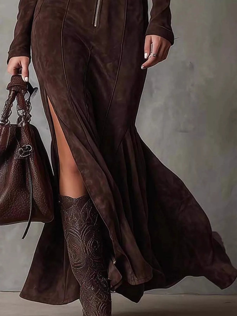 Person wearing a long brown suede dress with a slit, holding a matching handbag against a neutral background.