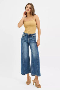 Woman wearing a yellow top and blue jeans on a white background