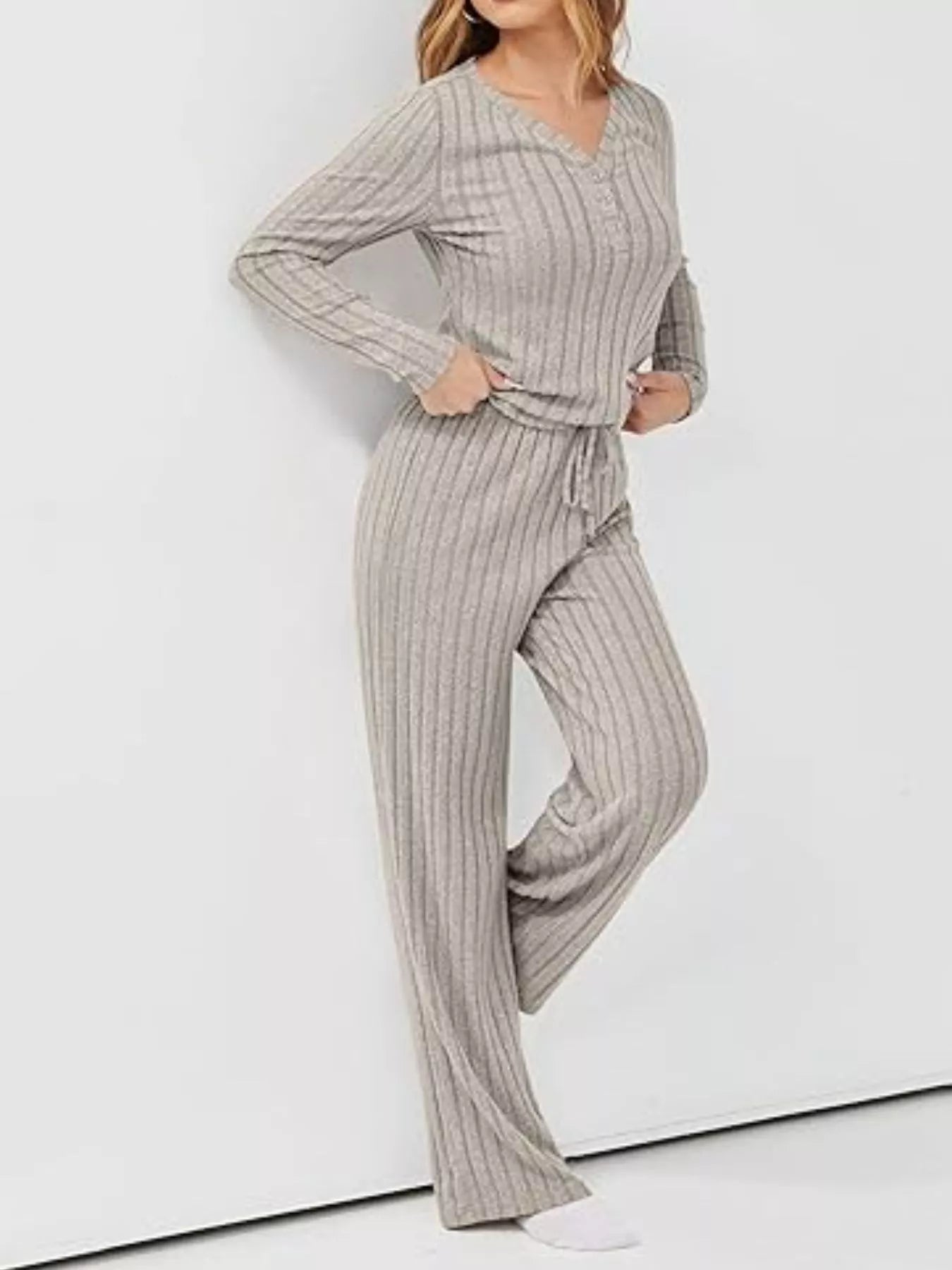 Woman wearing a gray ribbed knit outfit with a matching top and pants on a white background