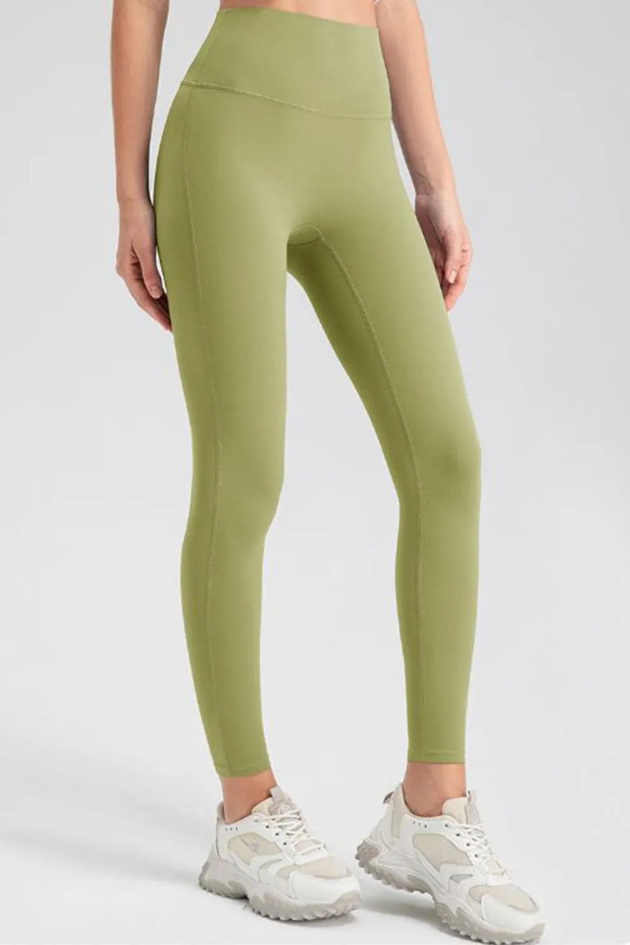 Person wearing green leggings and white sneakers on a white background