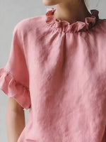 Close-up of a pink blouse with ruffled details on a plain background