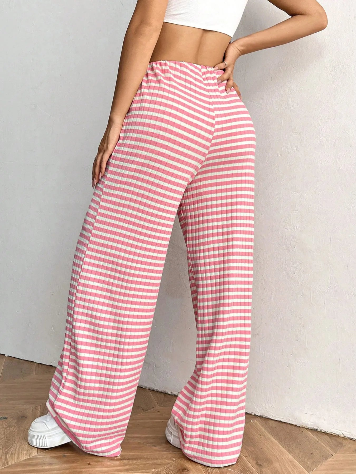 Person wearing pink and white striped pants on a plain background