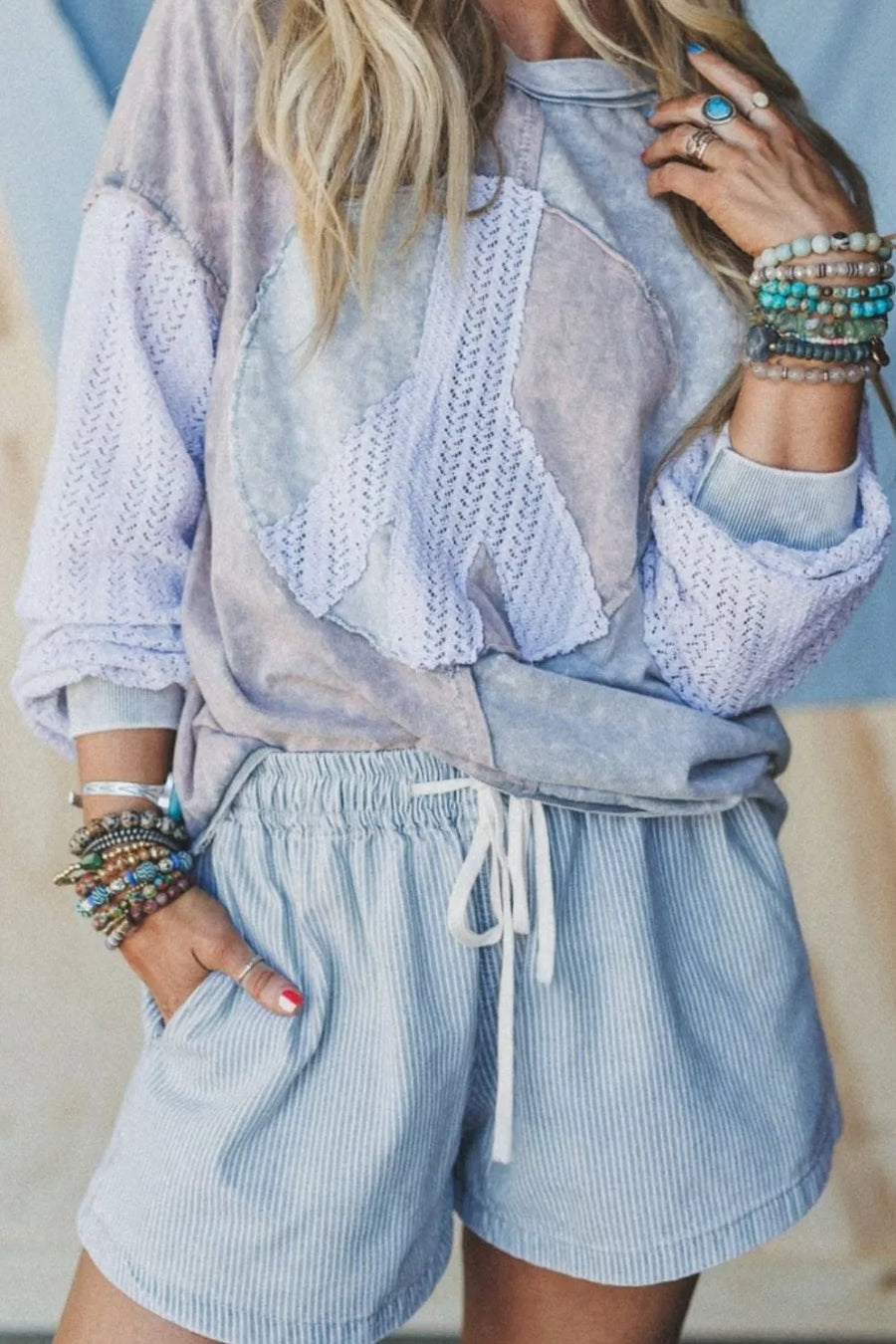 Person wearing a light blue outfit with a textured top and striped shorts, accessorized with bracelets.
