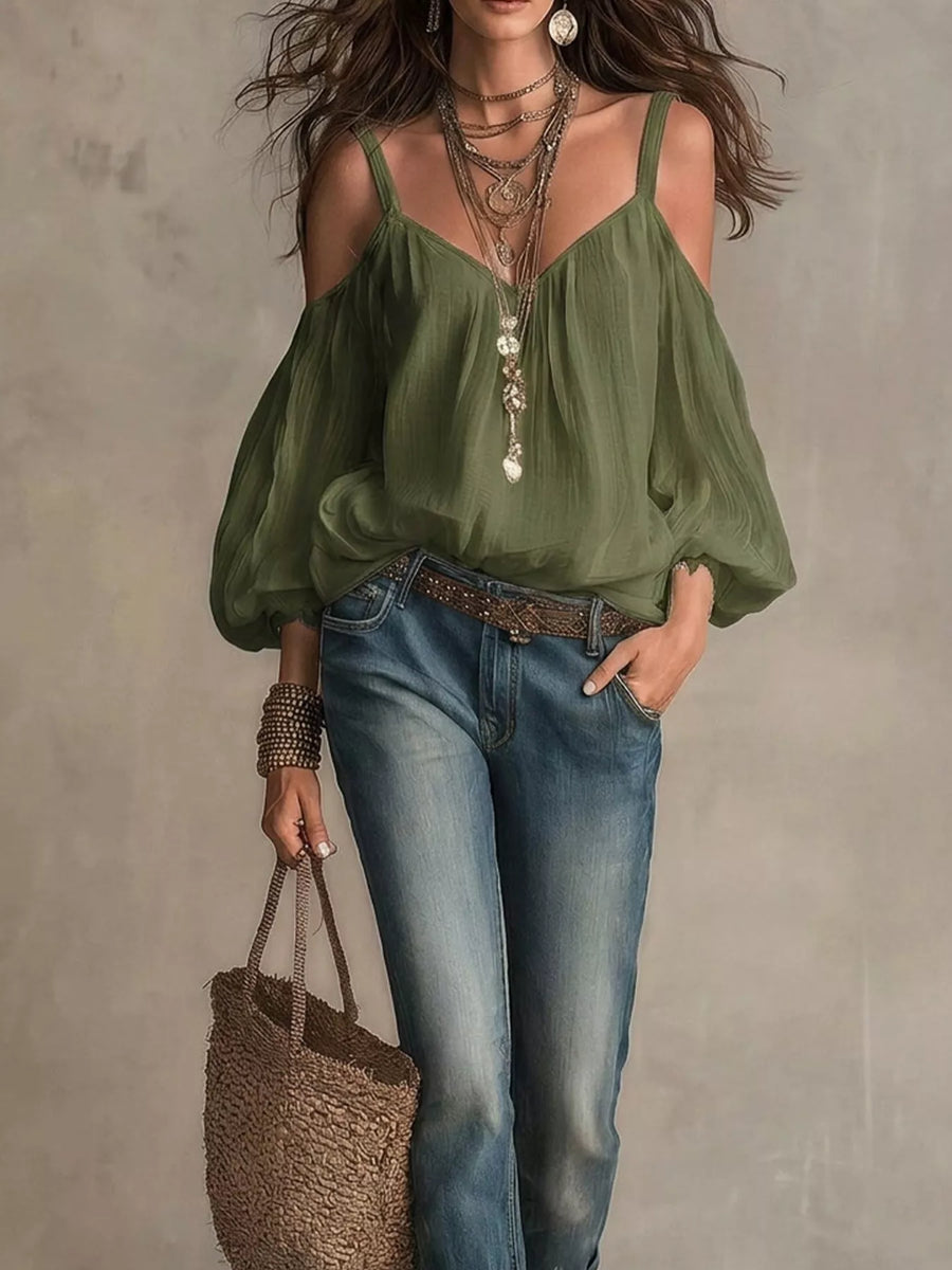 Woman wearing a green blouse and blue jeans, holding a straw bag against a neutral background