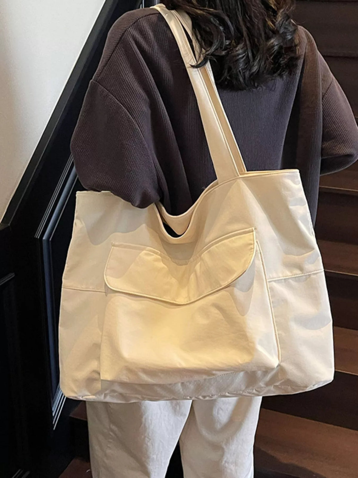 Beige tote bag worn by a person on a staircase