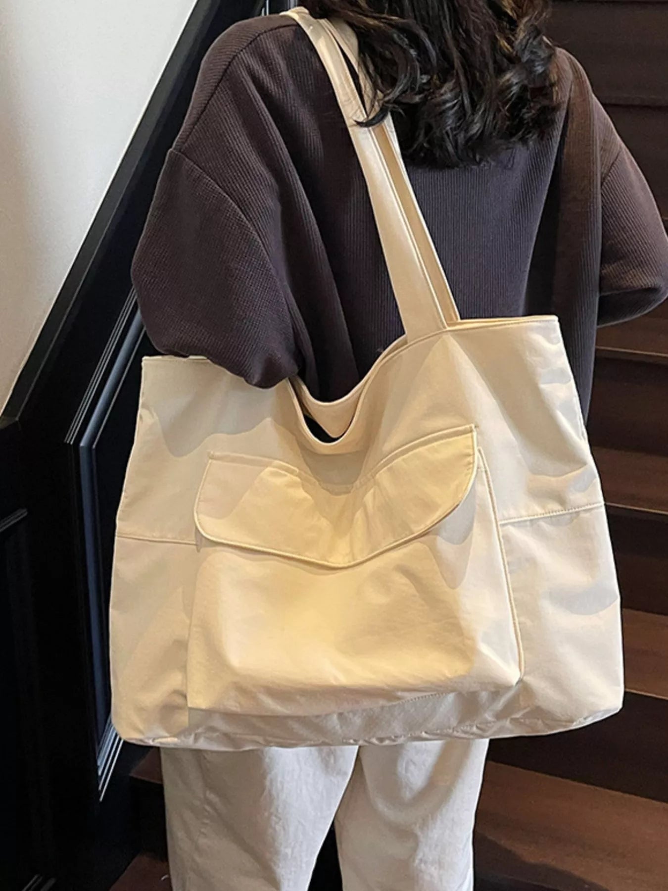 Beige tote bag worn by a person on a staircase
